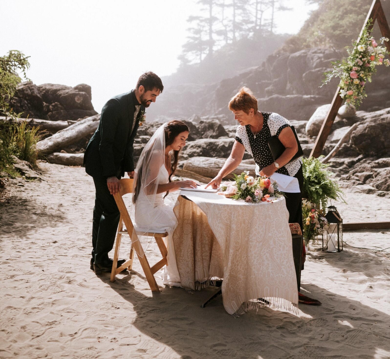 Couple signing wedding papers at a table on the beach