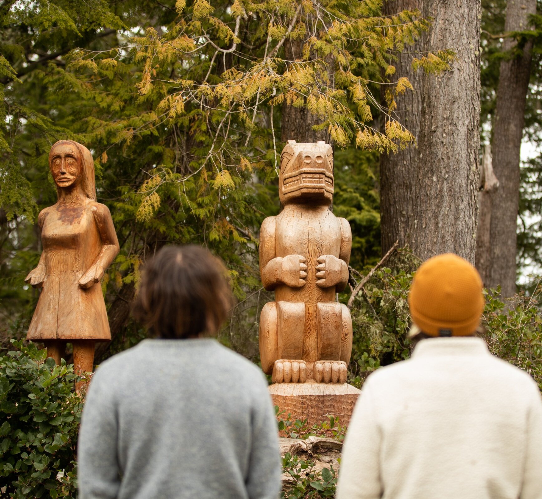 Two people looking at two totem poles