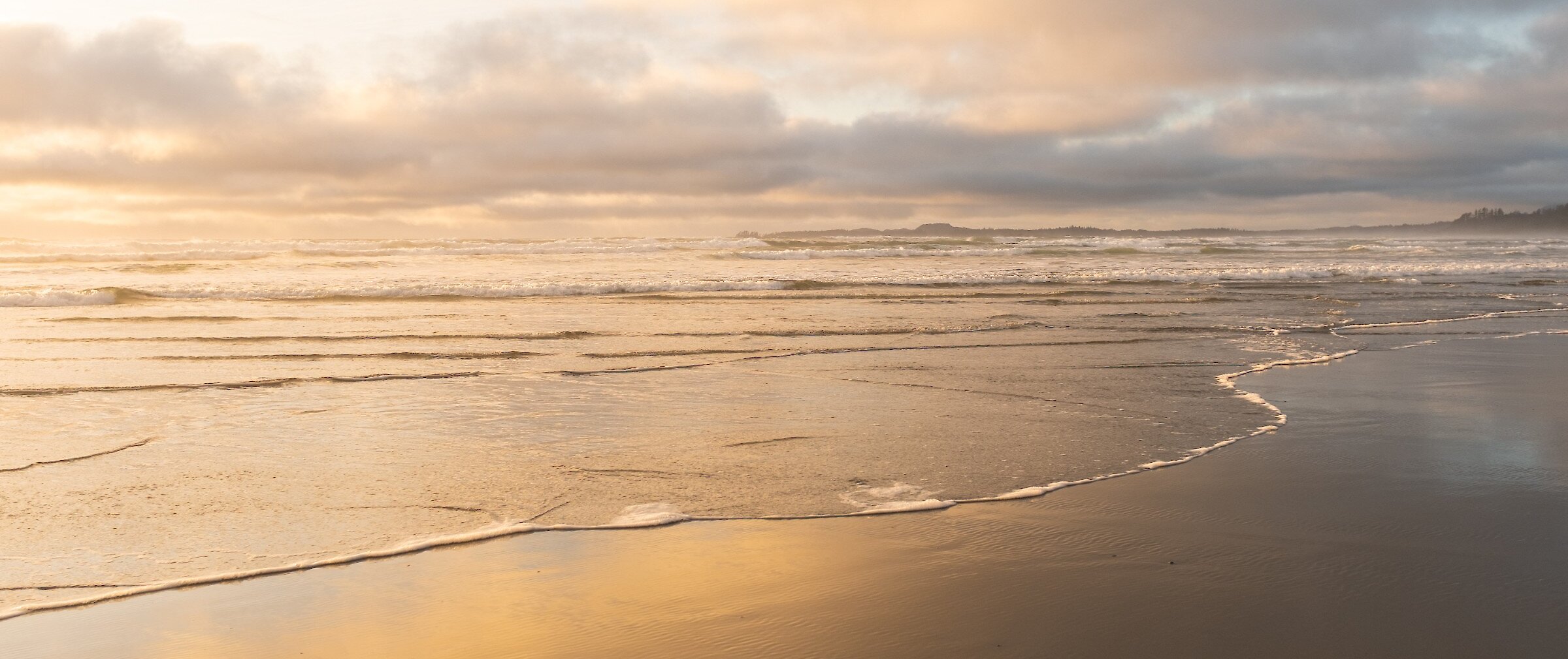 Sun and clouds reflecting in calm waters on the beach
